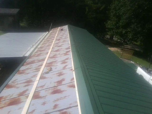 Old rusted panels beside newly installed green metal roofing — Wind Damage Roof Repair by Roofing Brothers in Rock Island
