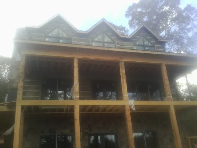 Dormers and porch framing on a large log home under construction — Roof Coating work by our crew in Rock Island