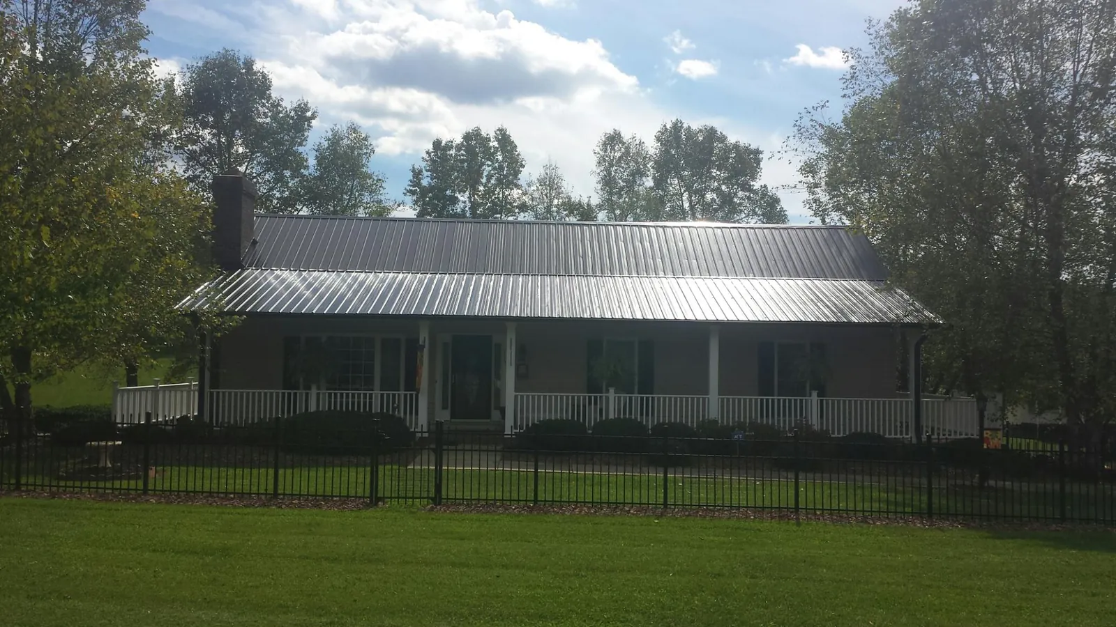 Gray metal roof on a brick ranch with a full width front porch — Gutter Guard Installation work by our crew in Rock Island